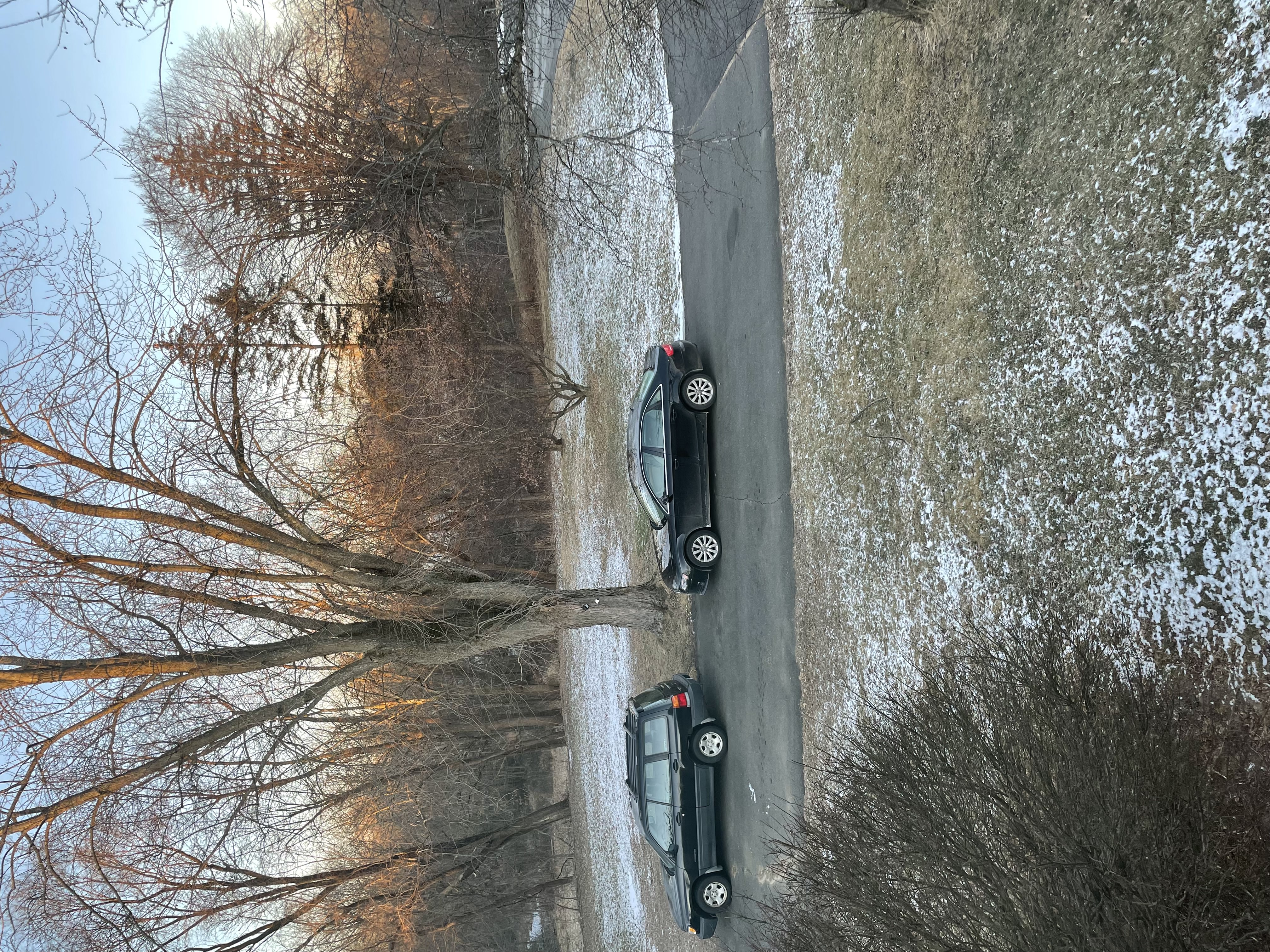 Iamge of a black Audi parked behind a black Subaru in a driveway. There is light snow on the ground from the day before.